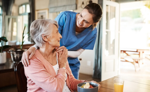 Shot of a young nurse checking up on a senior woman during breakfast at a nursing home